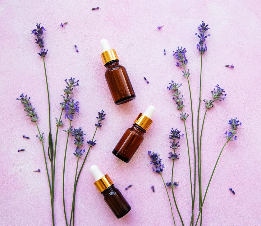 Flat lay composition with lavender flowers and natural cosmetic on pink concrete background