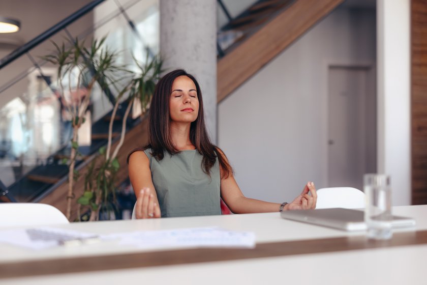 Eine Frau nimmt sich am Arbeitsplatz ein paar Minuten Zeit für Meditation.