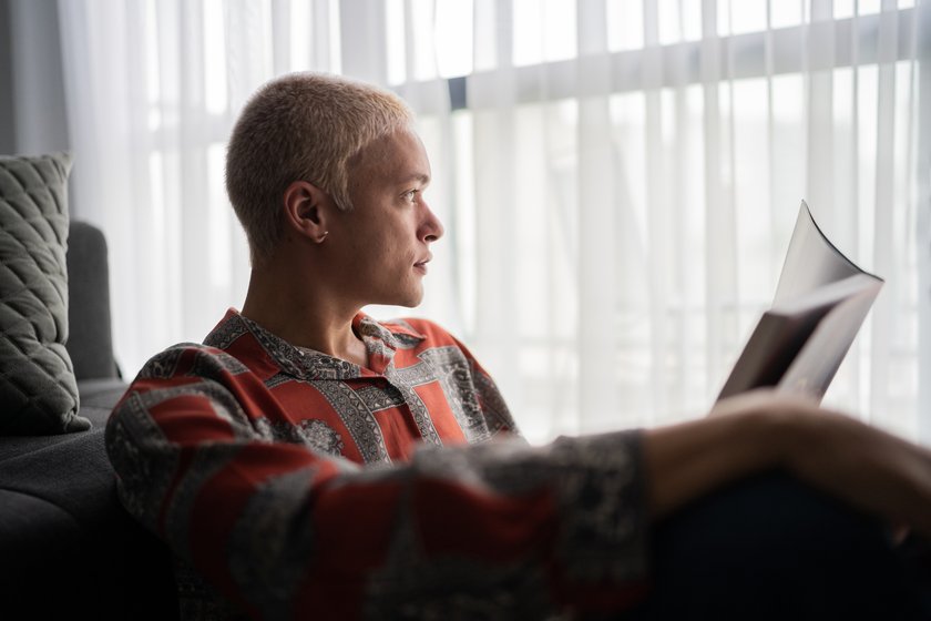 Junger Mann liest ein Buch und ist dabei nachdenklich