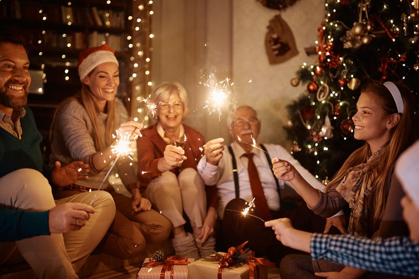 Cheerful extended family having fun with sparklers while celebrating Christmas together at home.