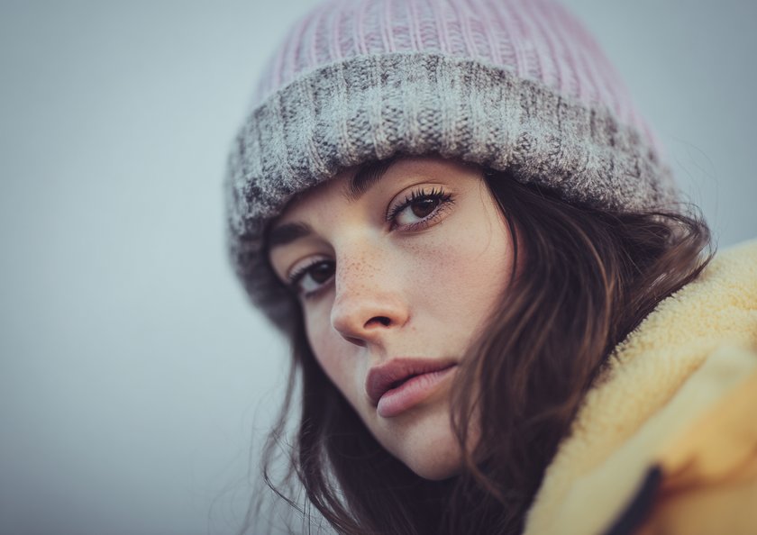 Junge Frau mit Mütze lächelt in die Kamera