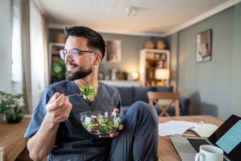 Mann isst Salat in MIttagspause