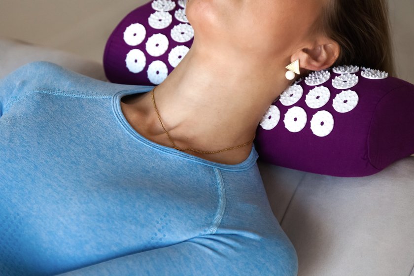 Frau entspannt sich mit Akkupressur-Kissen im Nacken