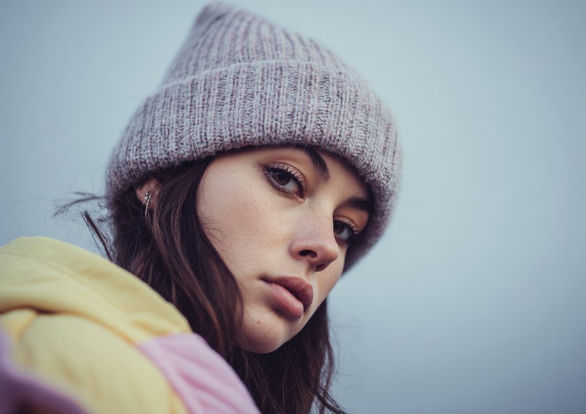 Junge Frau mit Mütze schaut in die Kamera