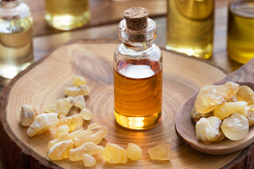 A bottle of frankincense essential oil with frankincense resin on a wooden table