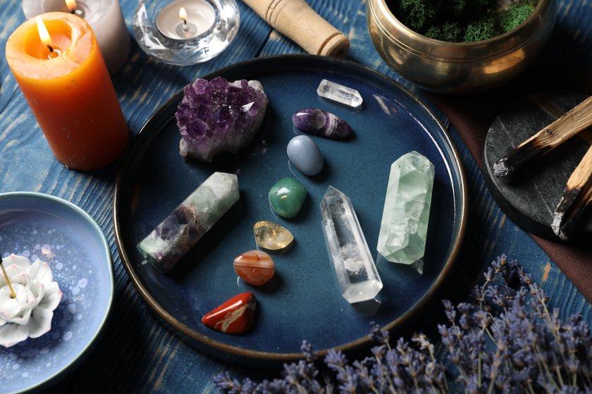 Chakra gemstones, lavender flowers, incense and burning candles on blue wooden table, closeup