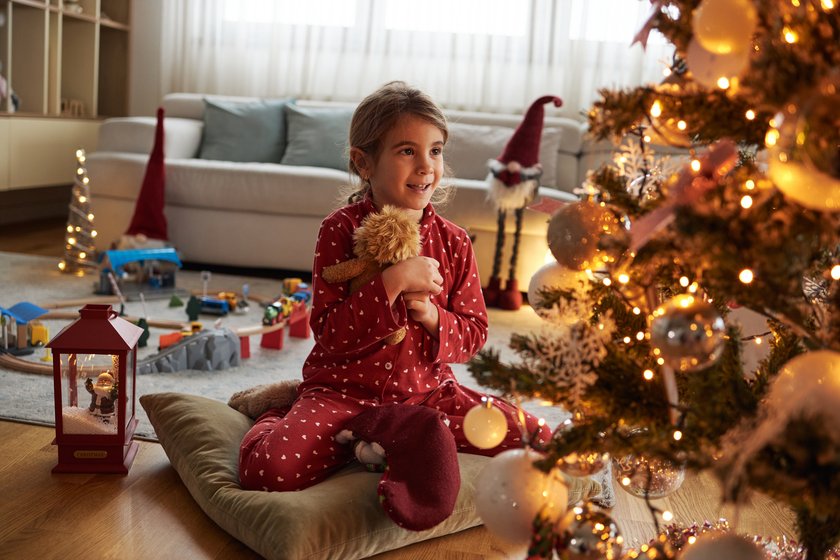 Happy girl on Christmas Eve opening Christmas stocking.